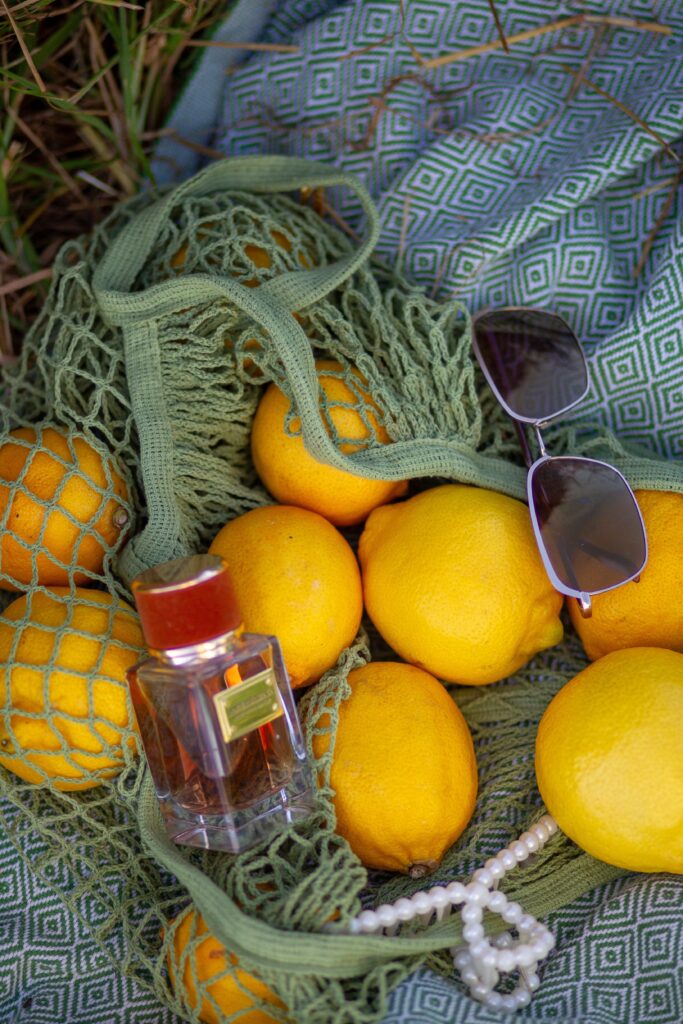 Bottle of fresh citrus perfume surrounded by lemons and orange blossoms, ideal for summer wear